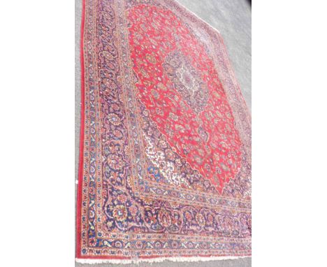 A large Iranian Kashan wool carpet of typical profuse floral design - 427cm X 295cm - moth damage