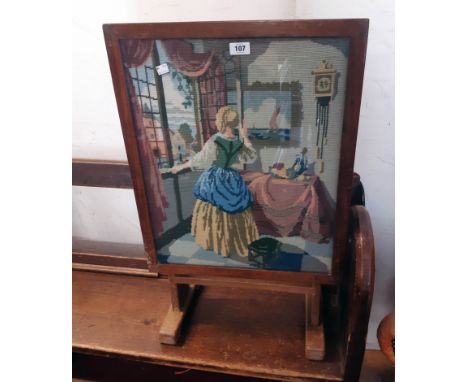 A 20th Century stained mixed wood tilt-top firescreen/tea table, with woolwork panel under glass to top