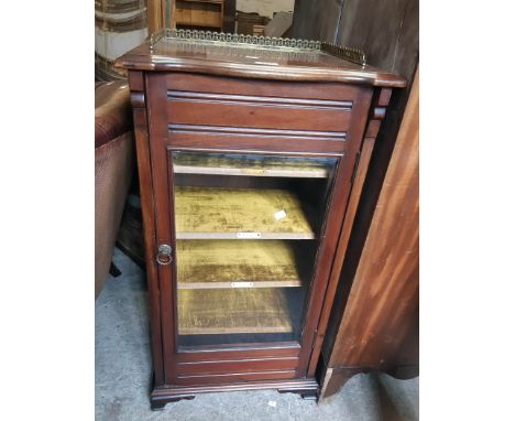 A 19" Edwardian walnut music cabinet with velvet lined shelves enclosed by a bevelled glazed panel door, set on moulded brack