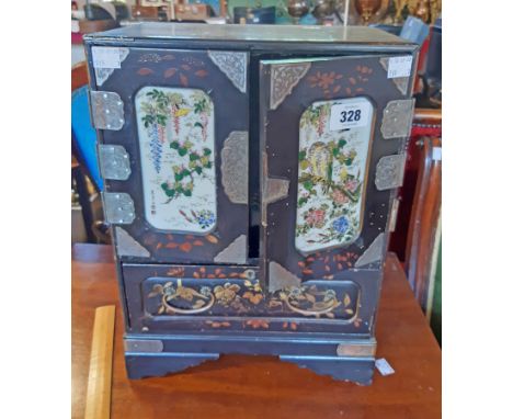 A 11 1/2" late Meji period Japanese lacquered cabinet with seven short drawers enclosed by a pair of decorative inset porcela