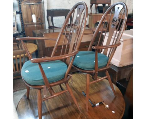 A set of four Ercol dark stained elm high hoop stick back chairs with pierced swan splats and green cushion swabs, comprising