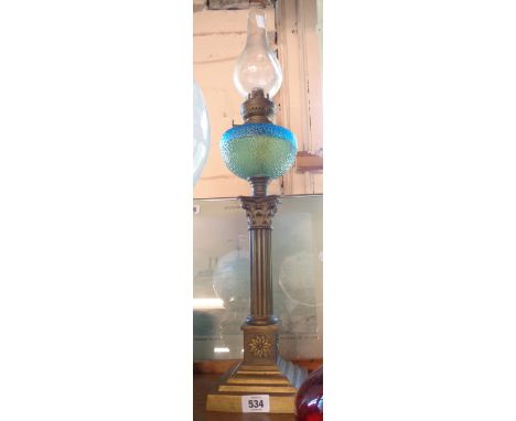 A brass column table oil lamp with moulded textured blue glass reservoir
