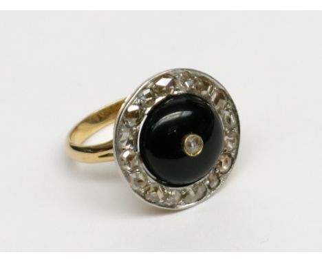 A high purity gold ring of bold target design, an outer circle of old cut diamonds surrounds a black onyx cabochon centred by