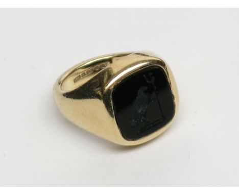 A 9ct gold signet ring set with a crested black onyx intaglio carved with a hawk holding a trident.