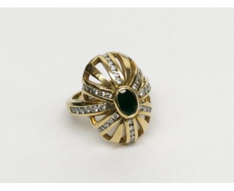 An 18ct gold post-war ring set with diamonds about a central emerald in the form of a cap, 14.8g.