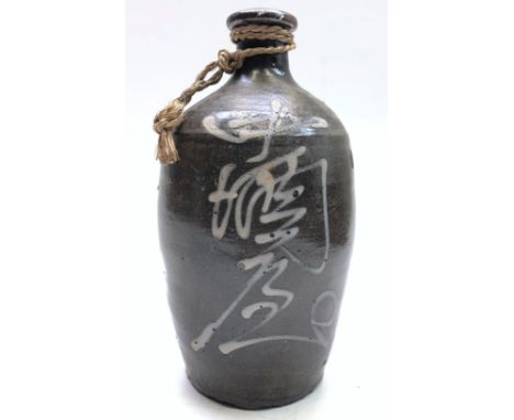 A Japanese stoneware saki bottle, decorated with calligraphy on a brown ground, height 25cm.