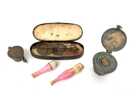 A set of bronze nesting weights, a similar set, a cased scale and two cheroot holders, one modelled as a pair of female legs.