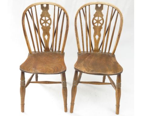 A pair of elm and beech kitchen chairs, 19th century, each with a wheelback splat and stick filled back above a solid seat on