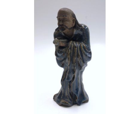 A Chinese blue glazed pottery figure of a man holding a begging bowl, height 25cm. 