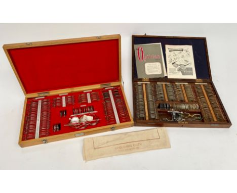 A vintage oak cased set of opticians' lenses, width 51cm, another similar set, a wall chart and two screens and a box of misc
