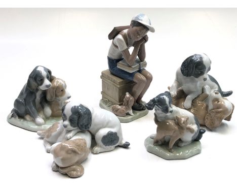 A Lladro figure of a schoolboy, seated with a dog at his feet, height 21cm, together with four Nao figures of puppies.