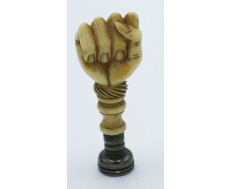 A 19th century seal in silver and ivory carved as a clenched fist the intaglio carved with a mailed arm holding a dagger, hei