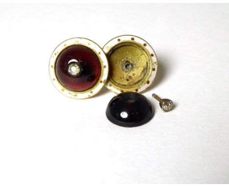 A pair of garnet and diamond earrings, a round cabocon garnet inset with an old cut diamond, to a white enamel and gilt frame