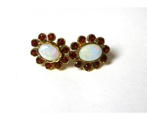 A pair of opal and hessonite garnet cluster earrings, an oval cabochon opal in a collet setting, within a cluster of round cu