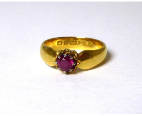 A 22 carat gold ruby ring, a round cut ruby in a claw setting with a collet border, to pinched shoulders, finger size L1/2The