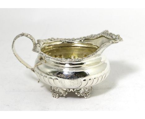 A George IV Silver Cream Jug, maker's mark rubbed, London 1821, squat circular with part fluted body, on four decorative lion