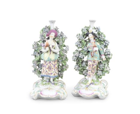 A pair of Derby candlestick figures of Italian Farmers, circa 1765Modelled as a well-dressed couple standing on ornate high-s