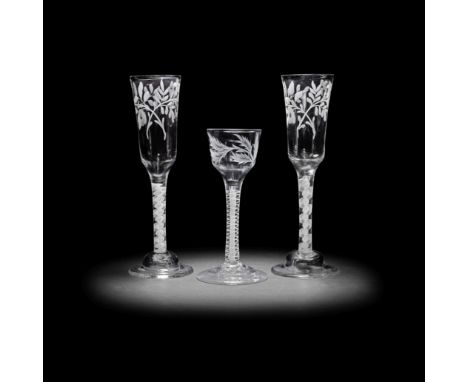 A pair of engraved opaque twist ale flutes and a wine glass, circa 1765The flutes with tall ogee bowls decorated with two flo