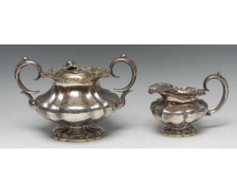 A Russian silver lobed milk jug and sugar basin, the borders applied with flowers and scrolls, the base with cover, flower fi