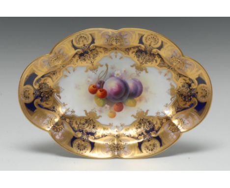 A Royal Worcester shaped oval plate, painted by Albert Shuck, signed, with ripe plums and cherries, within fancy gilt cartouc