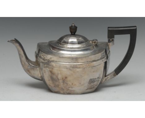 A George V silver faceted oval teapot, hinged domed cover, angular scroll handle, ebonised fittings, 27cm long, Barker Brothe