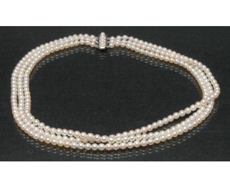A cultured pearl three strand necklace, uniform creamy pearls, each approx 4.7mm diameter, united by a 14ct white gold slide 