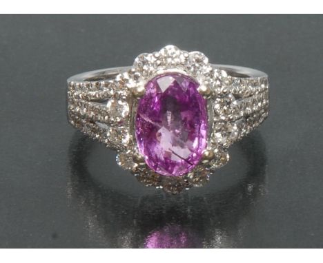 An oval pink sapphire and diamond cluster ring, central oval pink sapphire approx 9.5mm x 6.5mm x 4.2mm, surrounded by a band