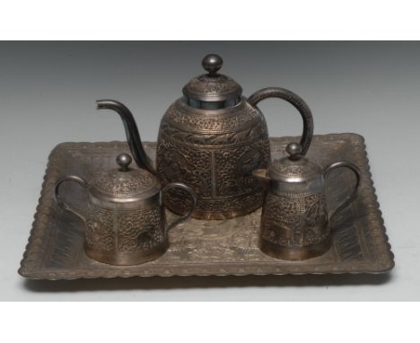 An Indian silver coloured metal three piece tea service on tray, comprising teapot, covered milk jug and sucrier, chased and 