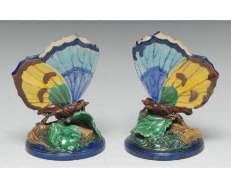 A pair of Royal Worcester majolica spill vases, as butterflies, upon leaves, in tones of blue and yellow, 13cm high, impresse