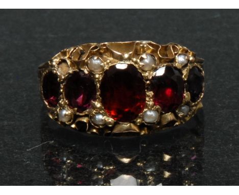 A Victorian garnet and seed pearl dress ring, five graduated oval garnets, each divided by a pair of small seed pearls (1 mis