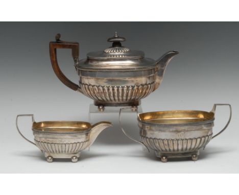 A George III silver three piece half-fluted tea service, comprising teapot, milk jug and sugar basin, angular scroll handles,