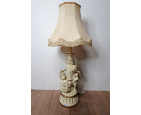 A CREAM AND GILT TABLE LAMP AND SHADE WITH CHERUB BASE DESIGN