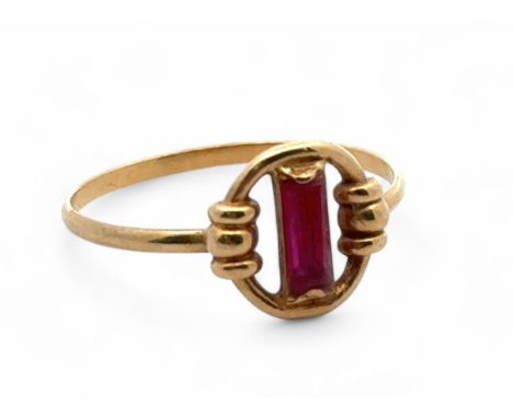 A yellow gold ring with a baguette cut ruby in a circular setting. Unmakred but tests as 18ct using XRF. Size N