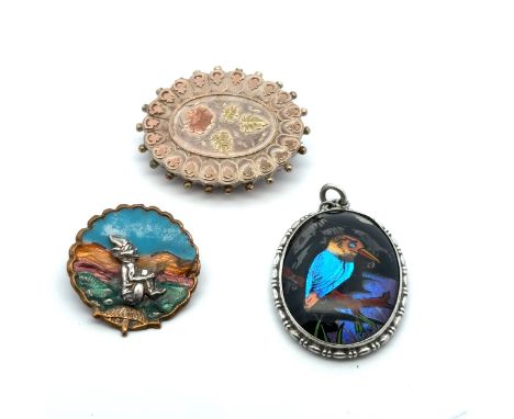 Three vintage jewellery items. A Victorian silver and applied gold brooch with floral design, an enamel Cornish pixie brooch 