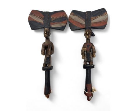 A pair of African Yoruba Shango staffs with carved figural design and large axe-shaped upper, strings with shell to carved ho