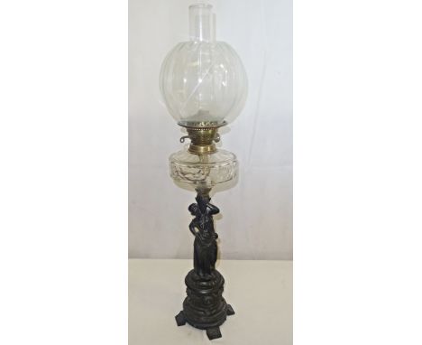 A cast-iron oil lamp in the form of a woman holding a basket with glass reservoir and bowl etc