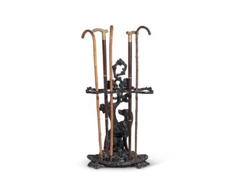 A CAST IRON STICK STAND  20TH CENTURY  With spaniel by tree back, drip pan, with assorted mostly modern walking sticks  72cm 