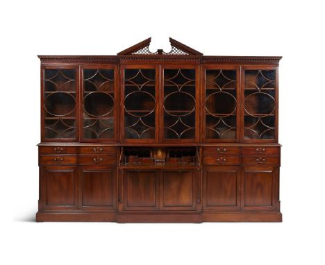 A MAHOGANY BREAKFRONT LIBRARY BOOKCASE IN GEORGE III STYLE, LATE 20TH CENTURY The central architectural pediment, above a den