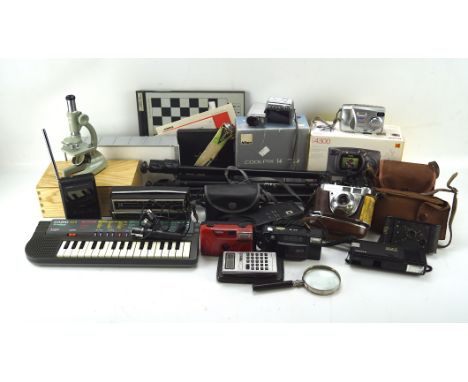 A collection of cameras and electronic equipment, including a tripod, Brownie camera, a magnifying glass, radio and more