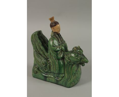 A CHINESE GREEN AND YELLOW GLAZED POTTERY FIGURAL ROOF TILE, formed as a man on a mythical bird, 22cm high.