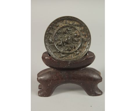 A CHINESE CIRCULAR BRONZE MIRROR, with carved soapstone stand, mirror 9cm diameter.