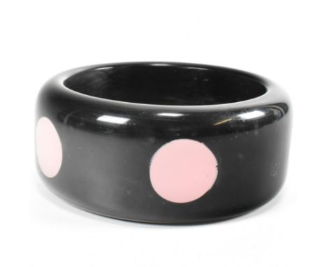 A vintage Bakelite dot injection bangle. The bangle in black colour-way having pink injection dots. Measures 3cm wide interna