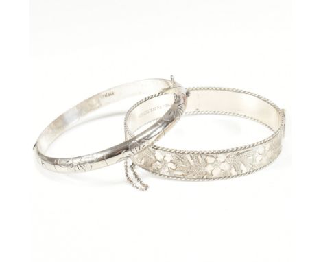 Two silver engraved hinged bangles. The bangles to include a hallmarked engraved silver bangle with floral engraving, twisted