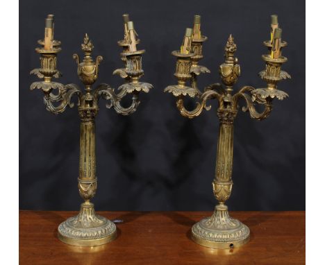 A pair of Louis XVI Revival ormolu four-light candelabra, each stop-fluted pillar surmounted by a flaming urn, campana sconce