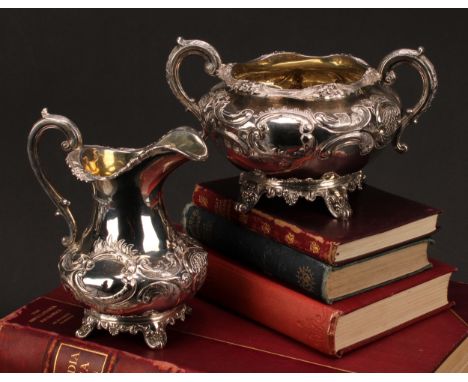 A Victorian Rococo Revival silver cream jug and sugar basin, chased with flowers and scrolls, scroll handles, splay feet, gil