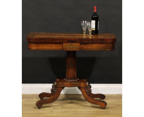 A Regency rosewood and brass marquetry card table, hinged top enclosing a baize lined playing surface, spreading cylindrical 