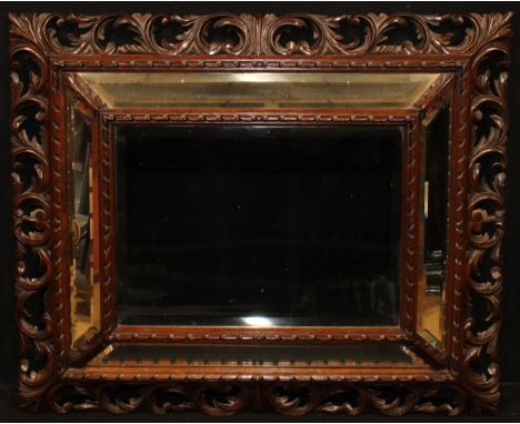A late 19th century oak looking glass, central bevelled mirror plate within a conforming cushion border, the frame carved wit