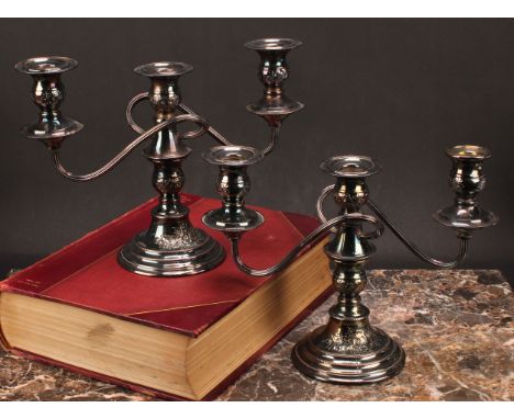 A pair of Elizabeth II silver three-light candelabra, ovoid sconces with detachable nozzles, adapting to singular candlestick