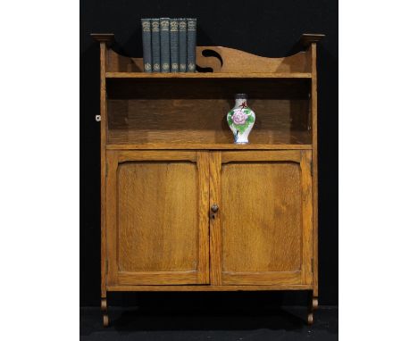An Arts &amp; Crafts oak wall cabinet, open bookcase shelf above a pair of panel doors, the sides pierced with stylised organ