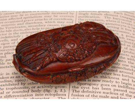 Snuff - a 19th century oval coquilla nut snuff box, carved with military trophies and stylised leaves, 7.5cm wide, c.1820 